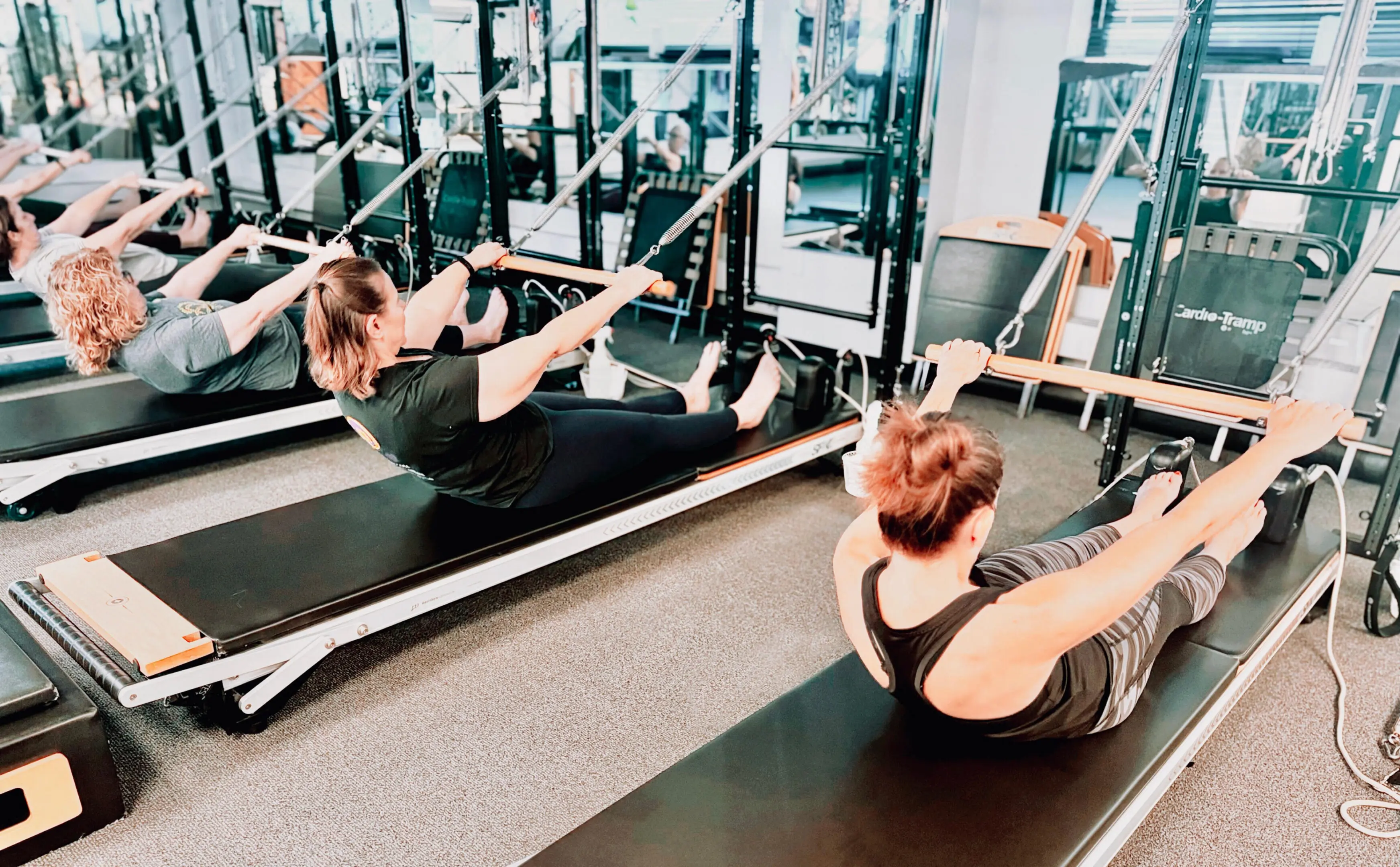 People exercising on Pilates reformer machines.