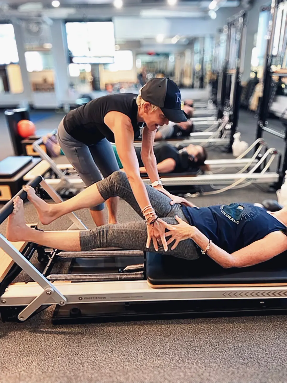 Instructor assisting with Pilates reformer exercise.