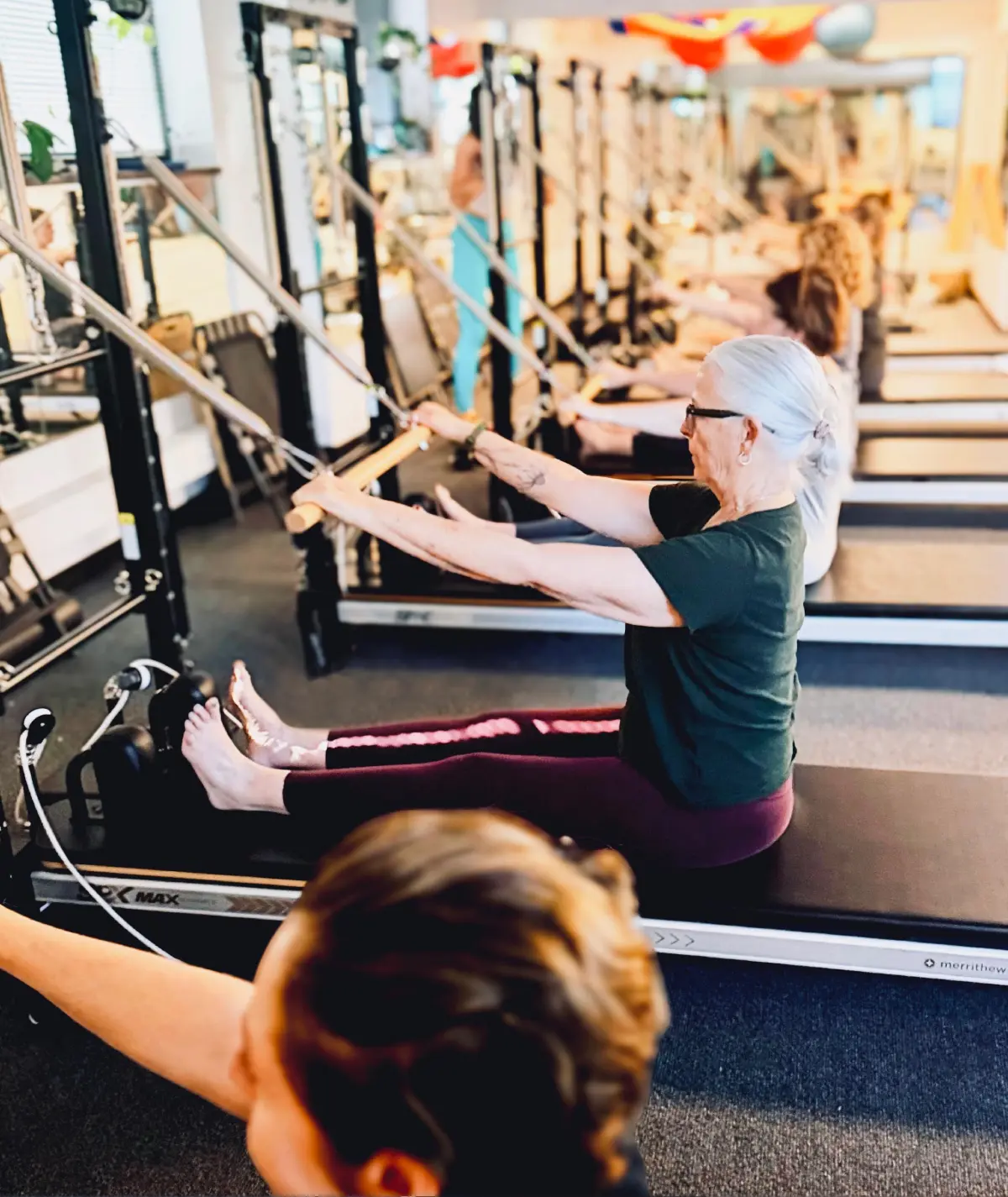 Women exercising on Pilates reformer machines.